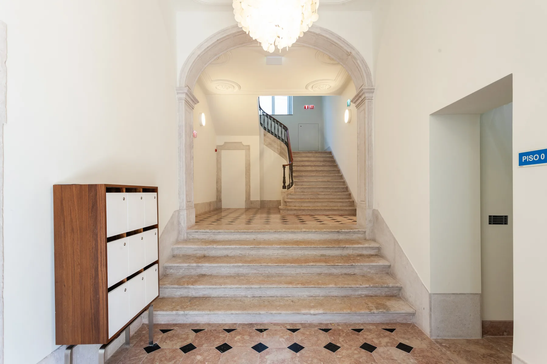 Una escalera luminosa con un arco decorativo y suelo de baldosas.