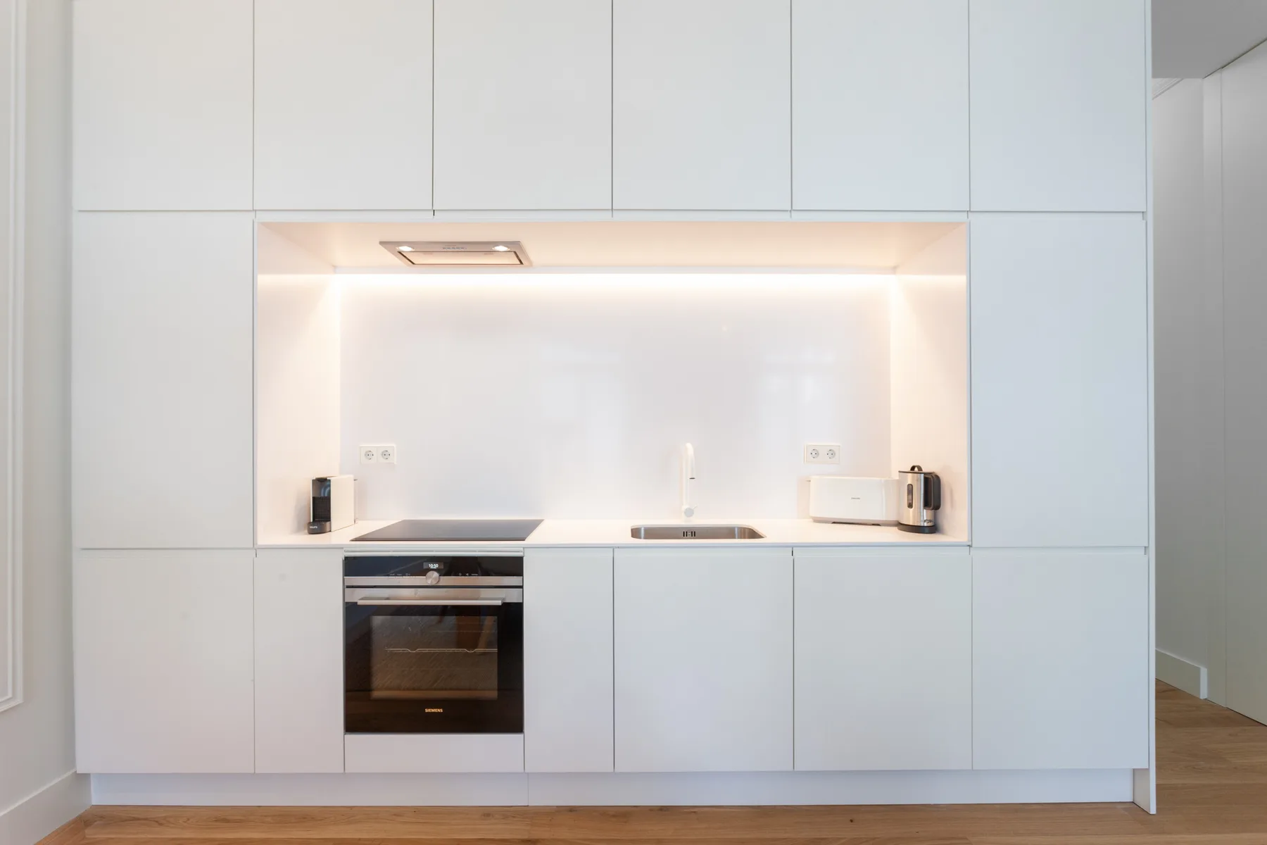Una cocina moderna con gabinetes blancos y electrodomésticos integrados.