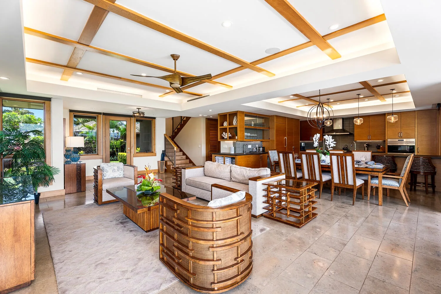 Espacio abierto de sala y comedor con cocina y grandes ventanas.