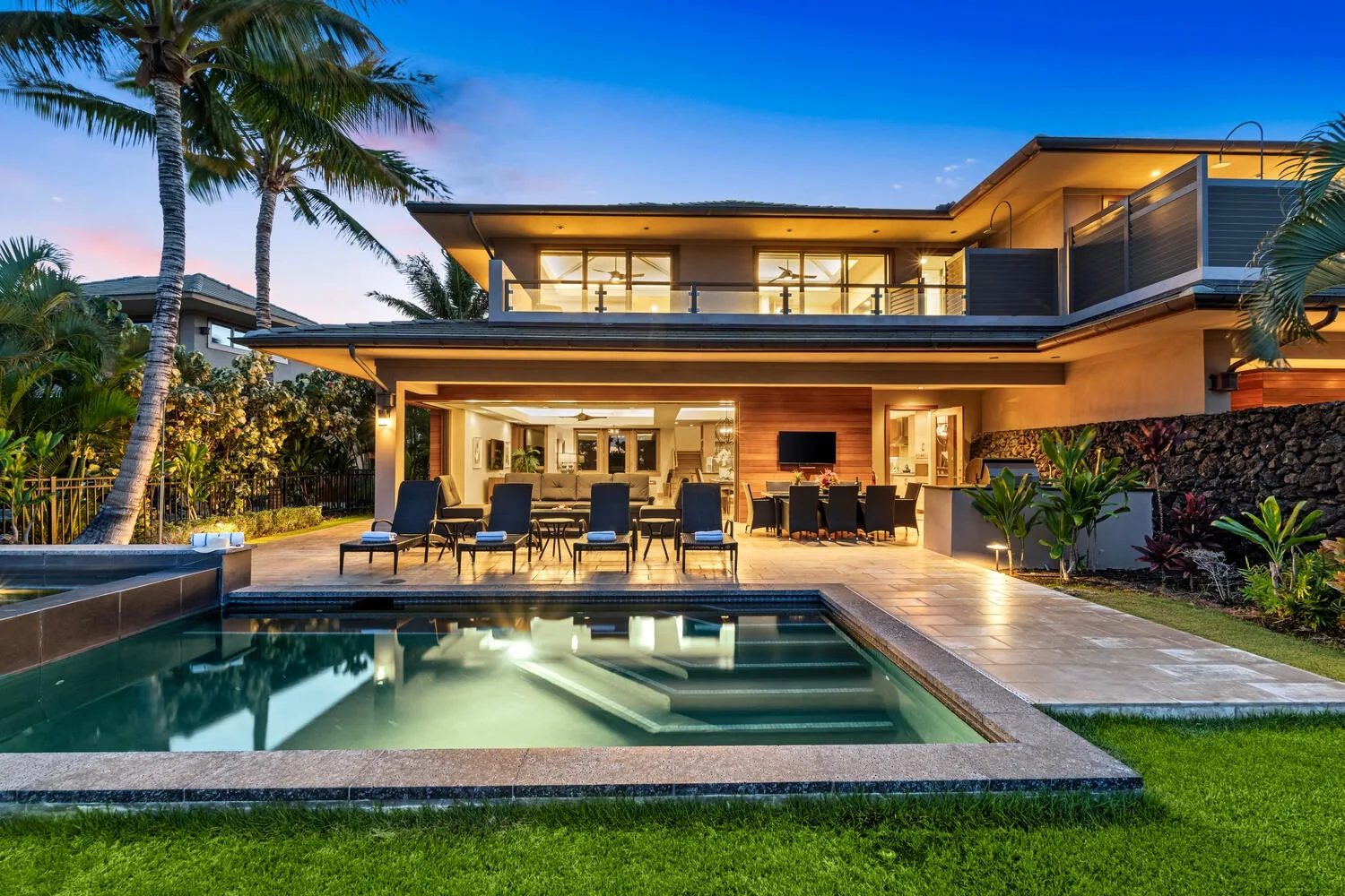 A modern house opens onto a swimming pool, with outdoor seating beneath the covered patio.
