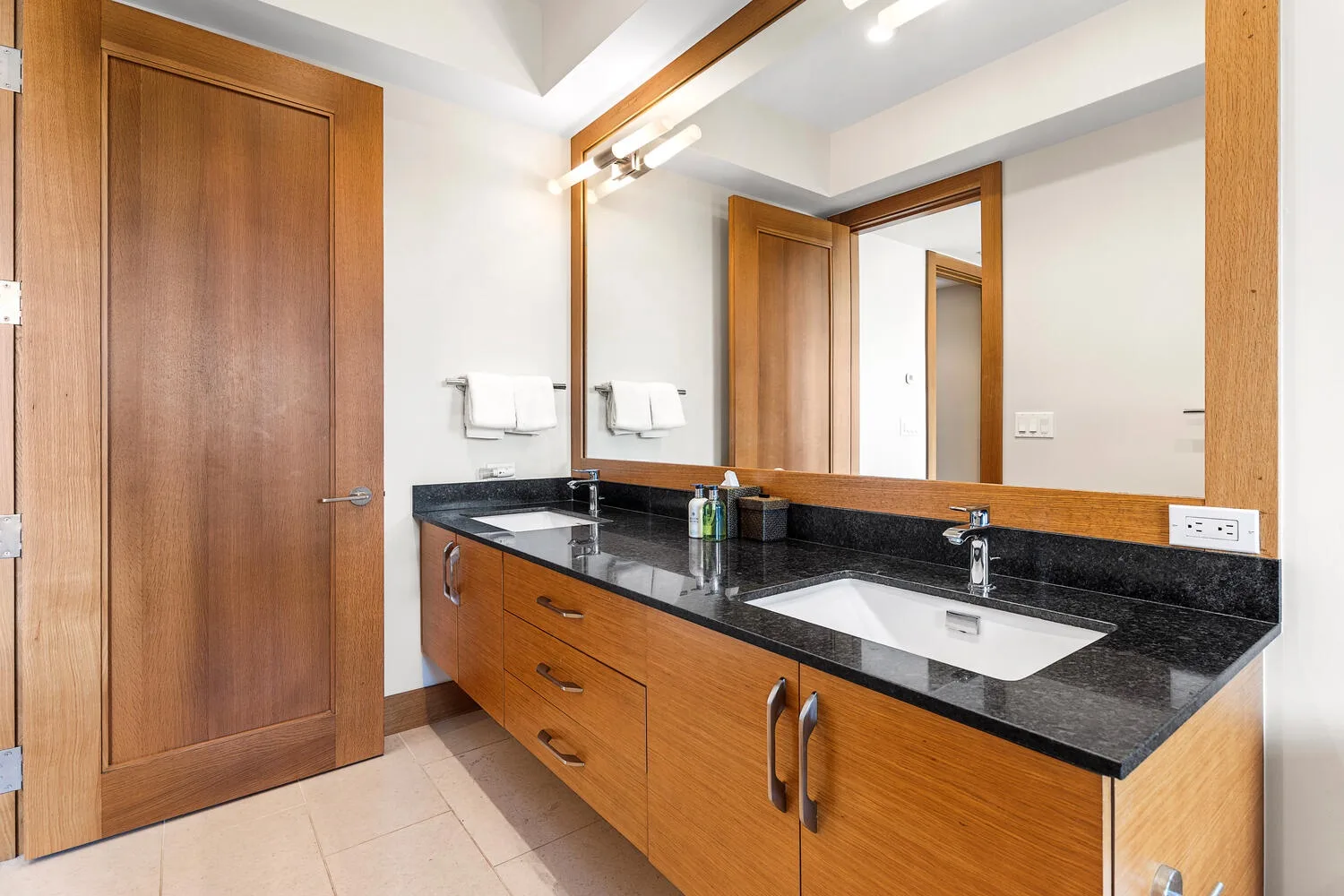 Un tocador de baño con una encimera larga, lavabo y espejo grande.
