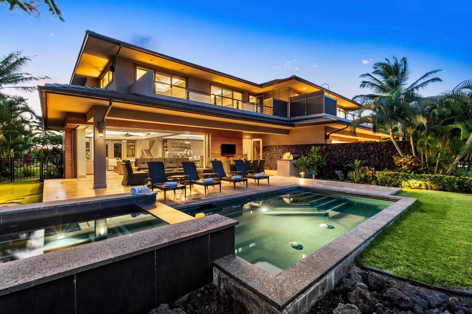Una casa moderna con piscina y asientos al aire libre al anochecer.