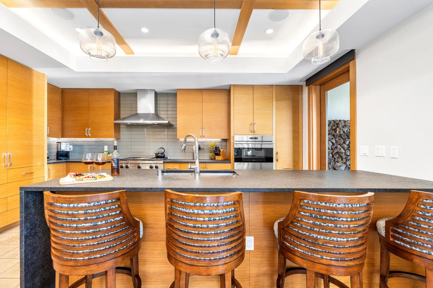 Una cocina moderna con gabinetes de madera, una isla central y asientos de barra.