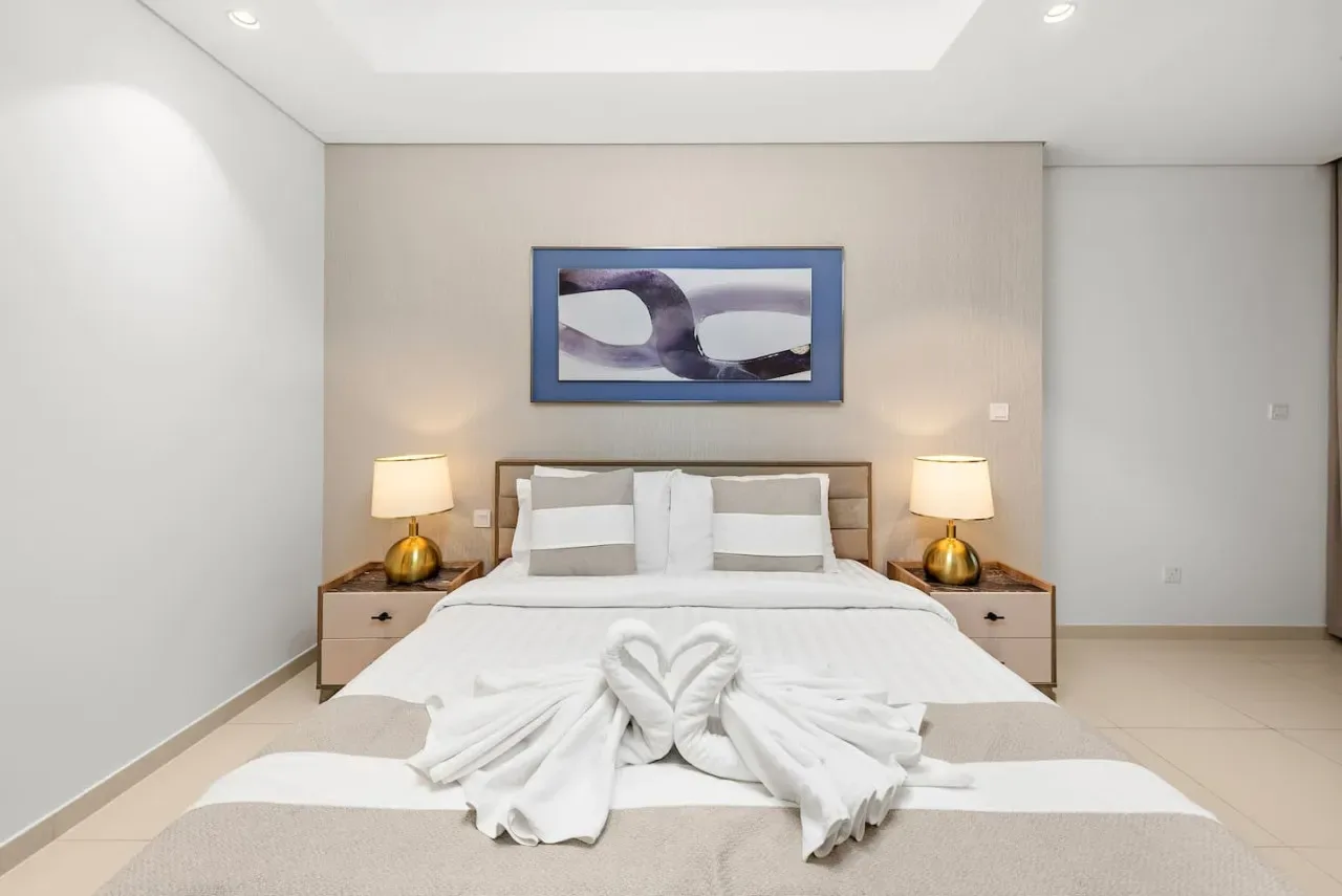 Un dormitorio con una cama tendida y una obra abstracta enmarcada encima.