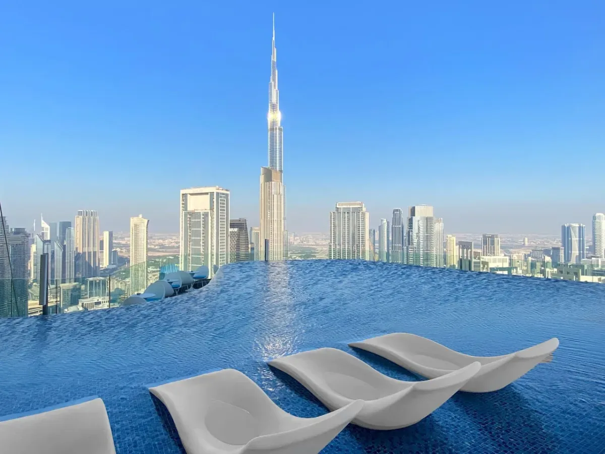 Una piscina infinita da a un horizonte urbano, con asientos junto al agua.