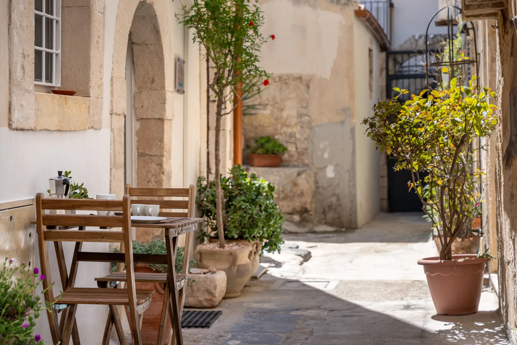 Un patio de piedra soleado con asientos al aire libre y plantas en macetas.