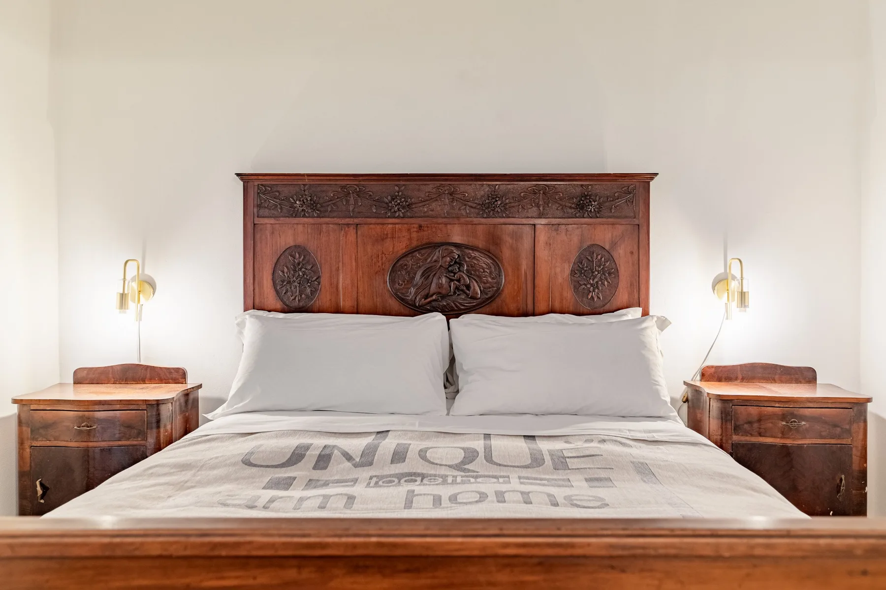 Un dormitorio con una cama grande bajo un cabecero de madera ornamentado.