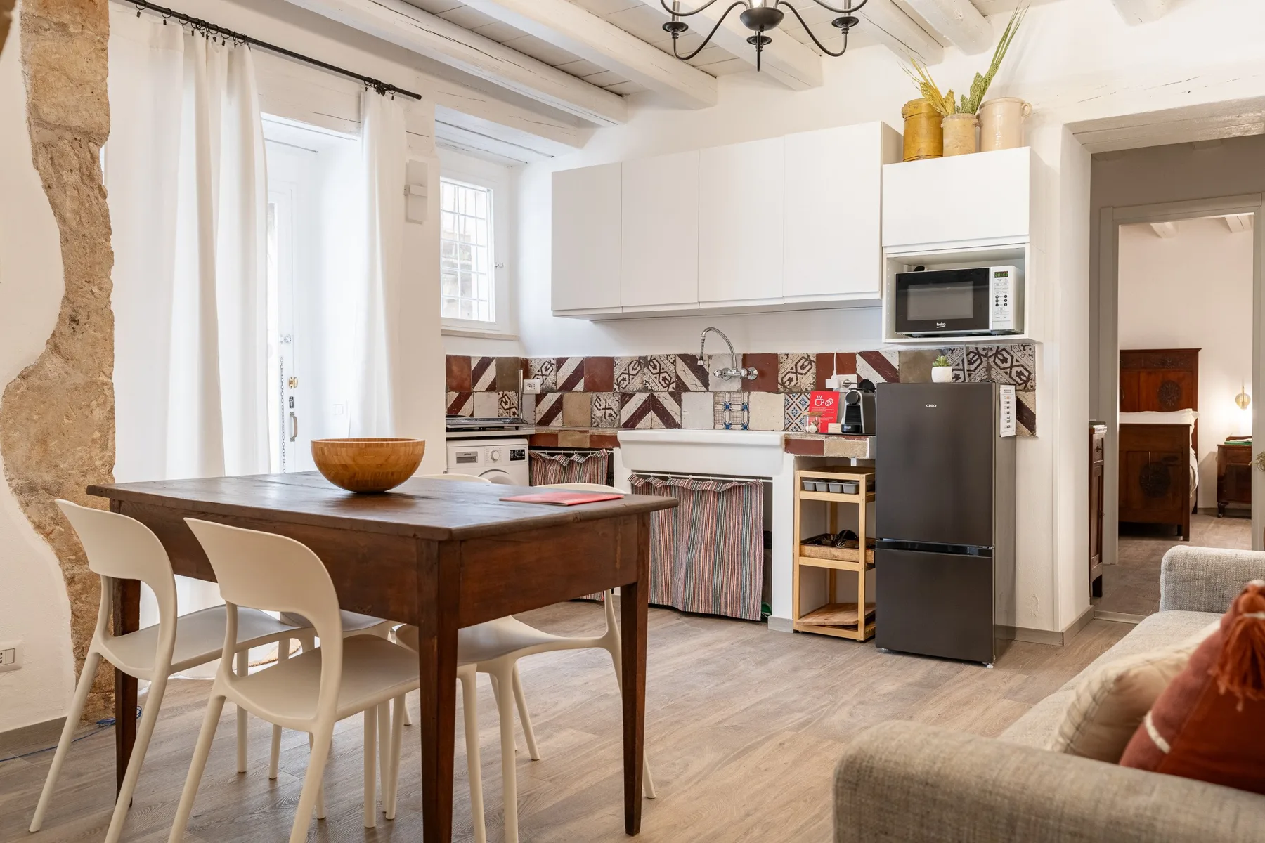 Una luminosa cocina con comedor, mesa de madera y armarios blancos.