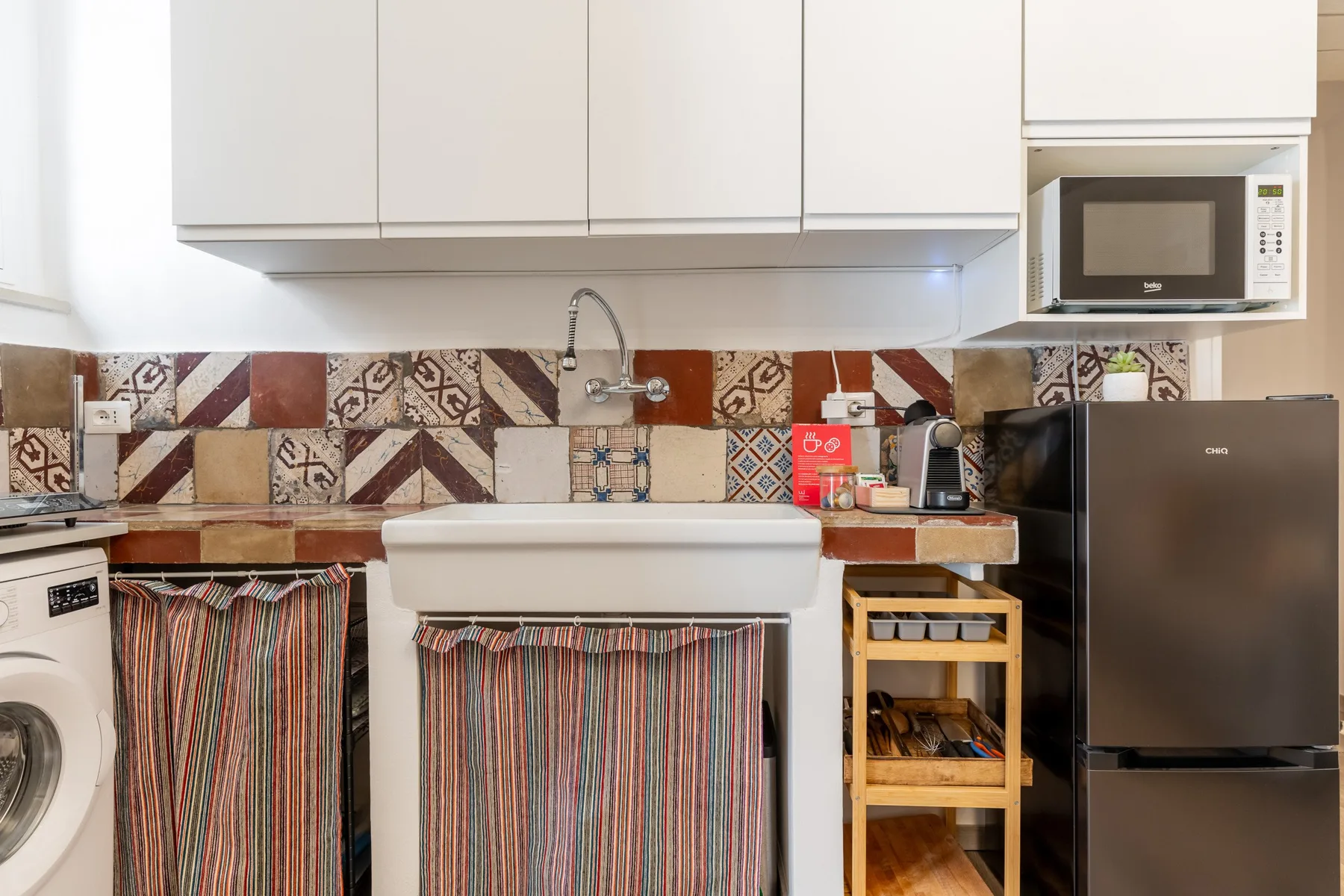 Una cocina compacta con fregadero, armarios superiores y refrigerador.