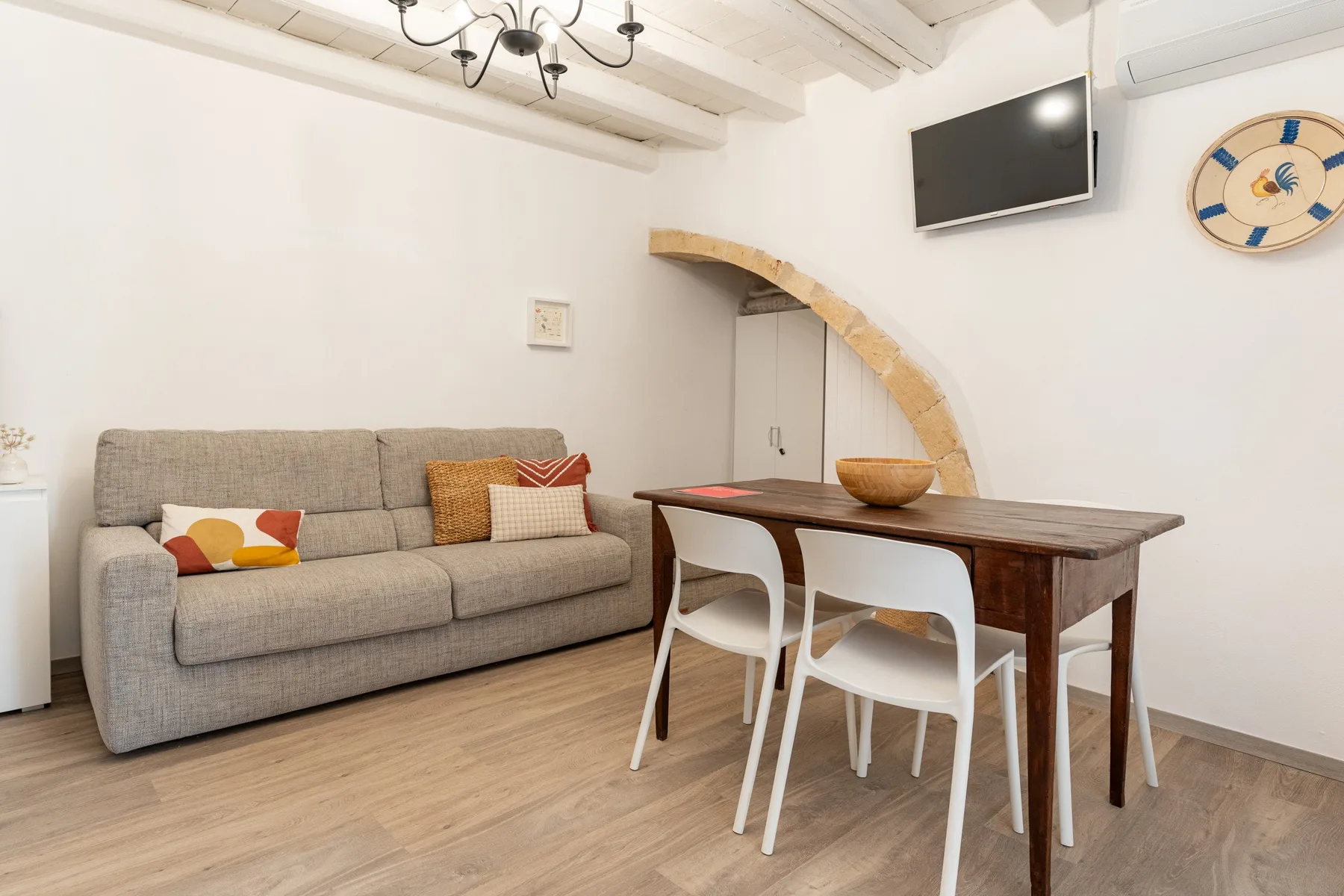 Una luminosa sala de estar y comedor con un sofá gris y una mesa de madera.