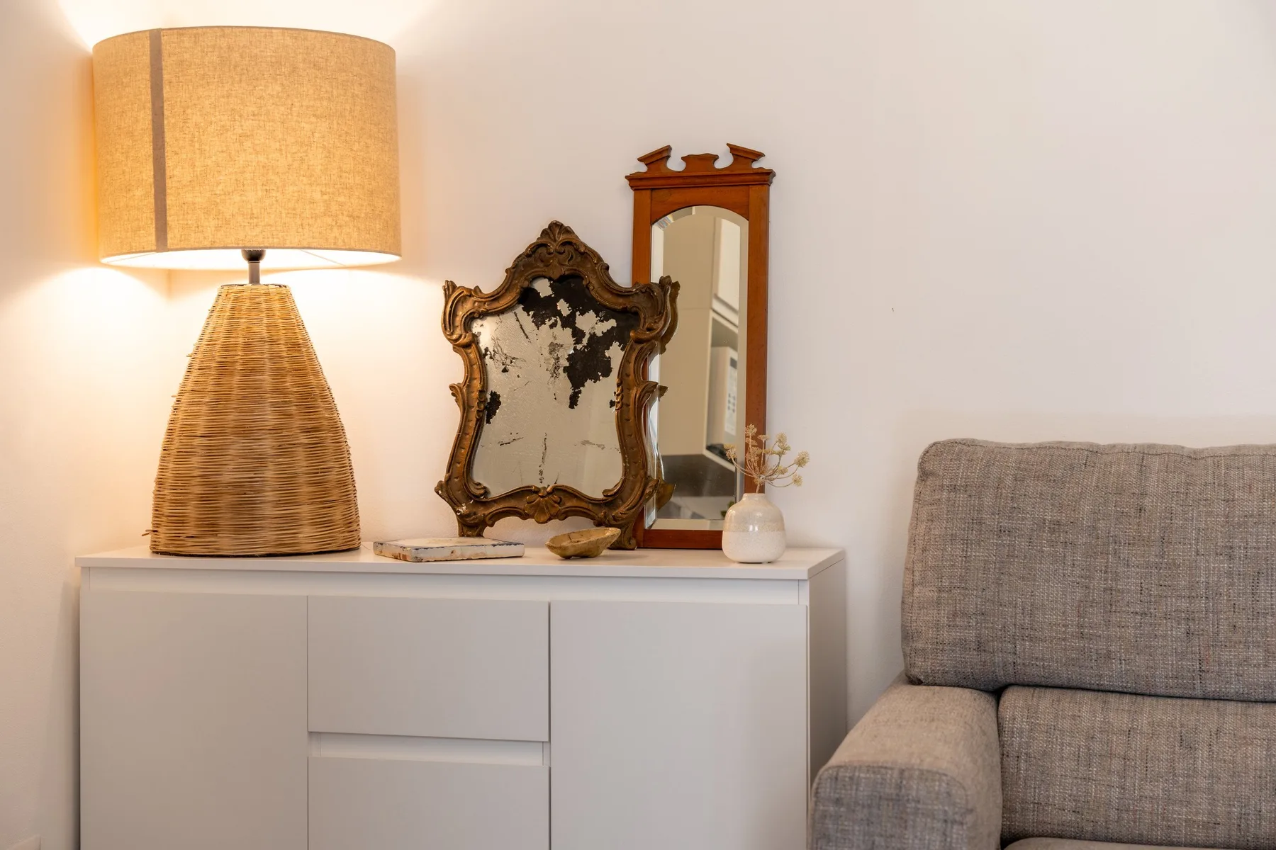 Una zona de estar con un sillón tapizado gris junto a un mueble blanco.