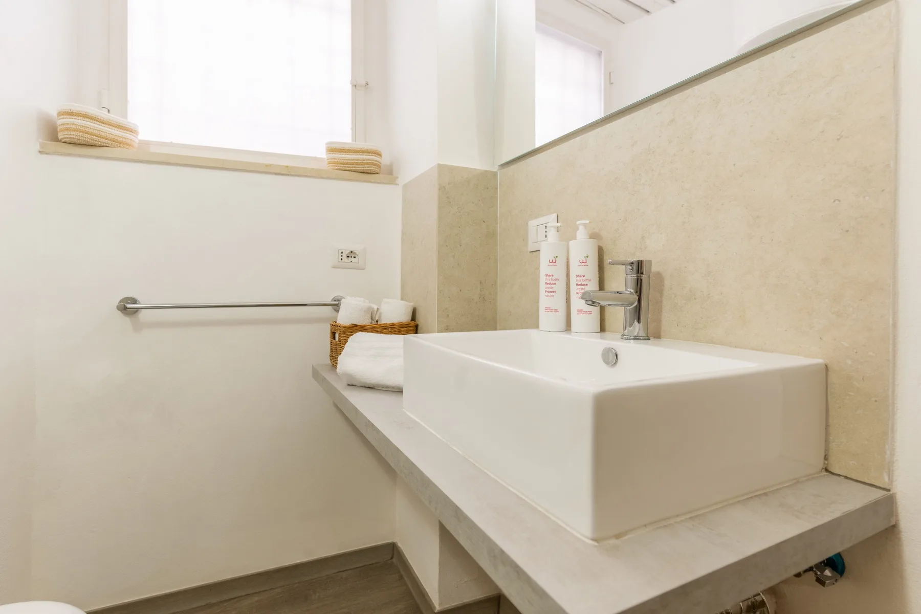 Un baño luminoso con un lavabo rectangular debajo de una ventana.
