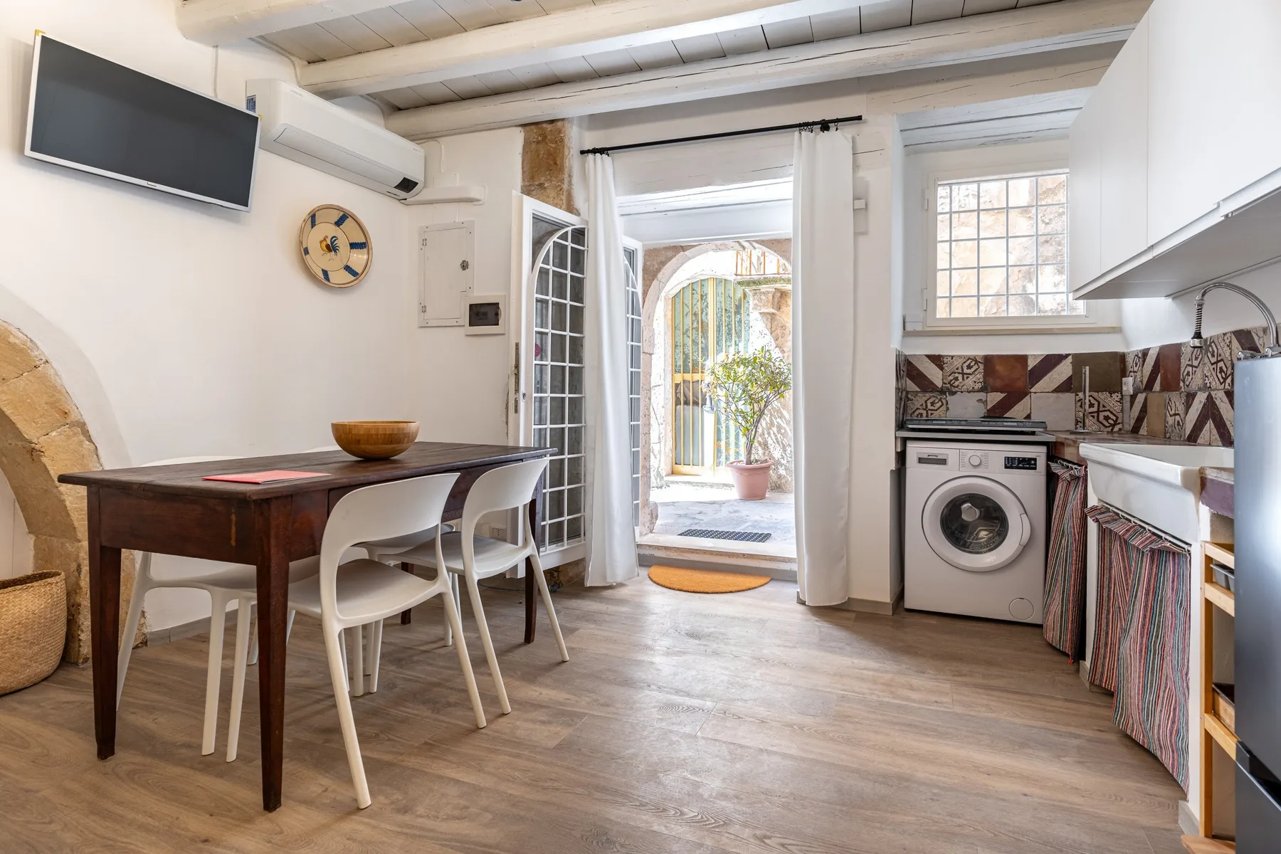 Una cocina luminosa con comedor se abre a un pequeño patio por puertas de vidrio.