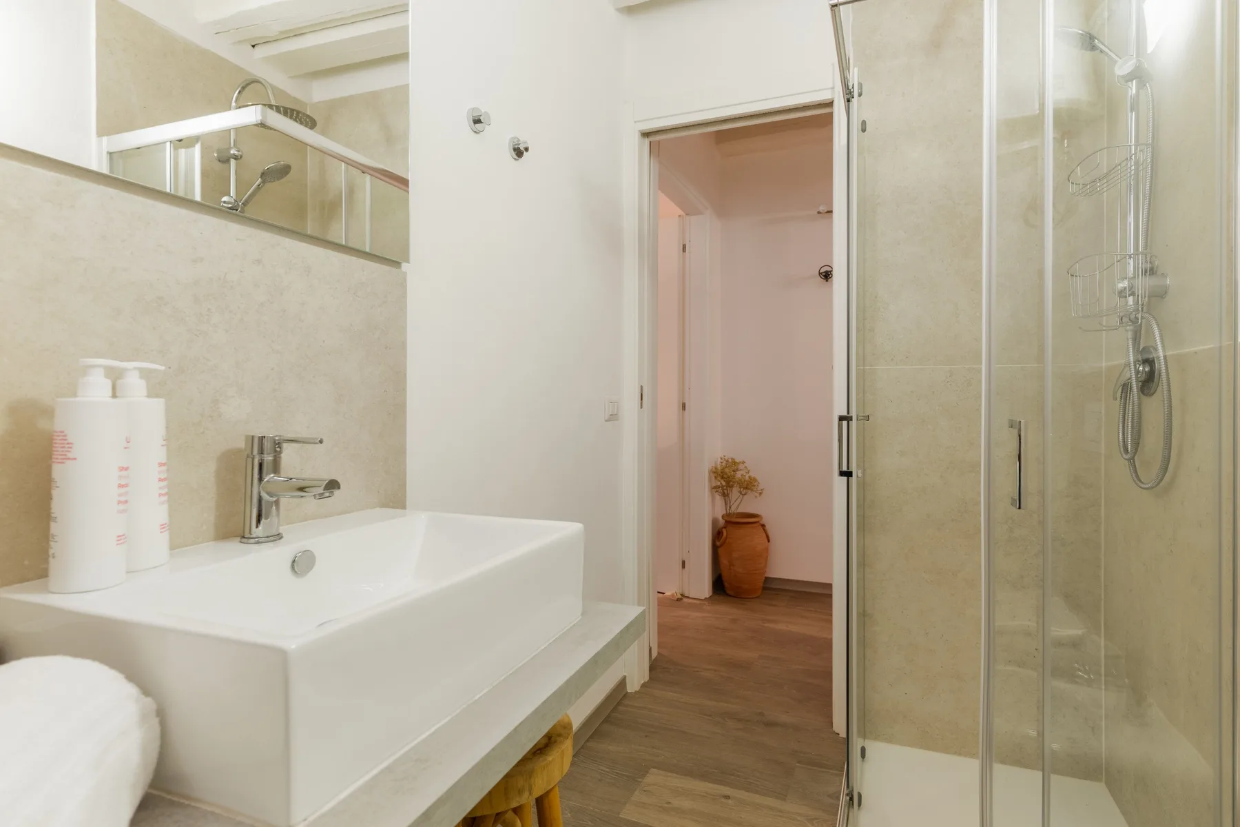 Un baño con lavabo blanco, un espejo grande y una ducha de vidrio.