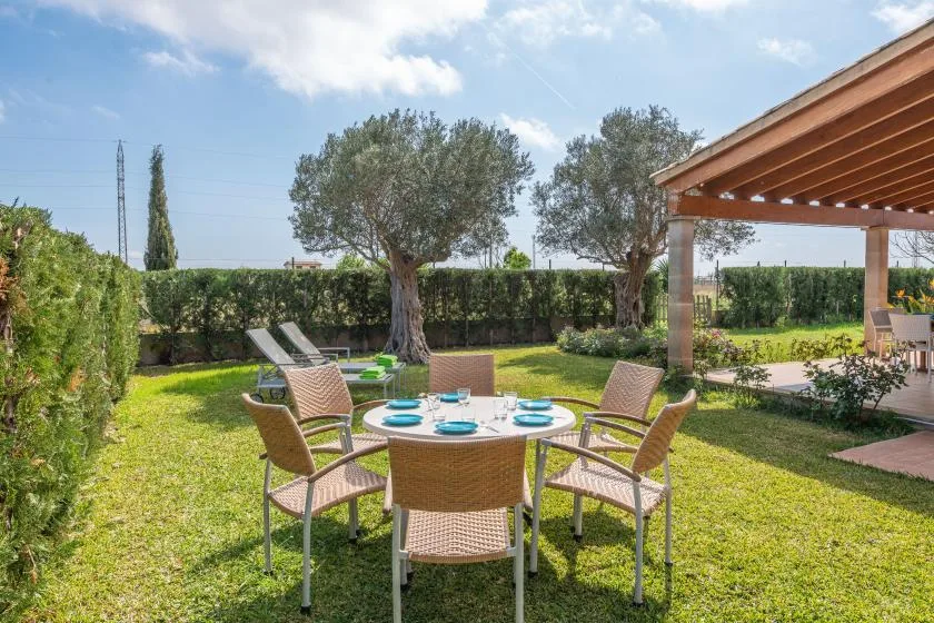 Outdoor dining area with a round table and seating on a grassy lawn.