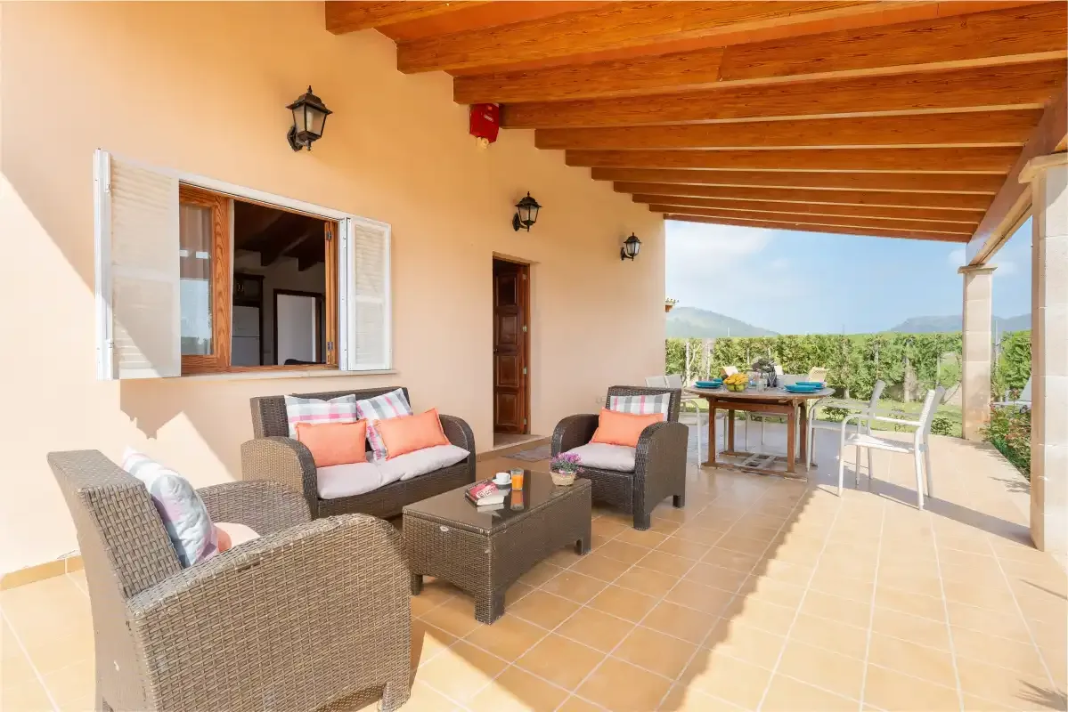 A covered outdoor seating area with a table overlooking the countryside.