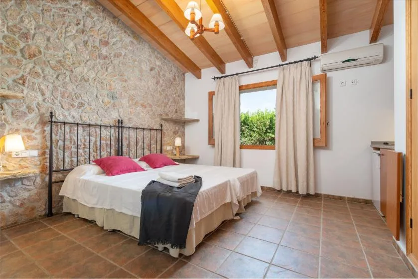 A bedroom with a double bed beneath exposed wooden ceiling beams.