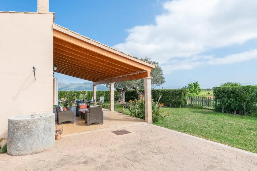 A covered outdoor patio with seating opens onto a green garden.