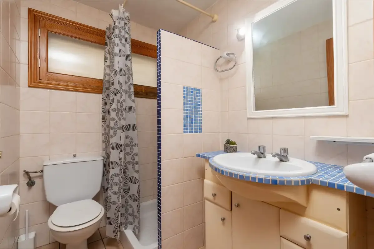 A tiled bathroom with a shower, toilet, and vanity with a sink.