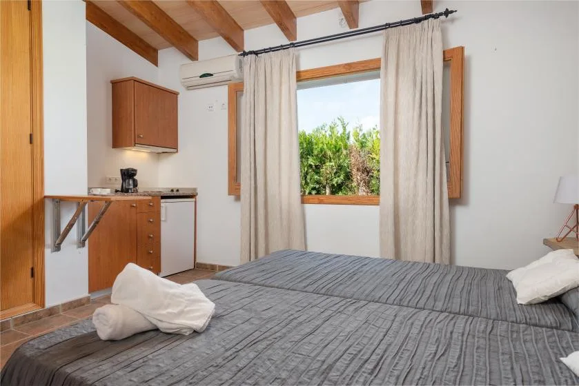 A bedroom with a kitchenette, a window, and gray bedding.