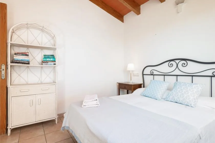 A bedroom with a bed, bedside table, and white shelving unit.
