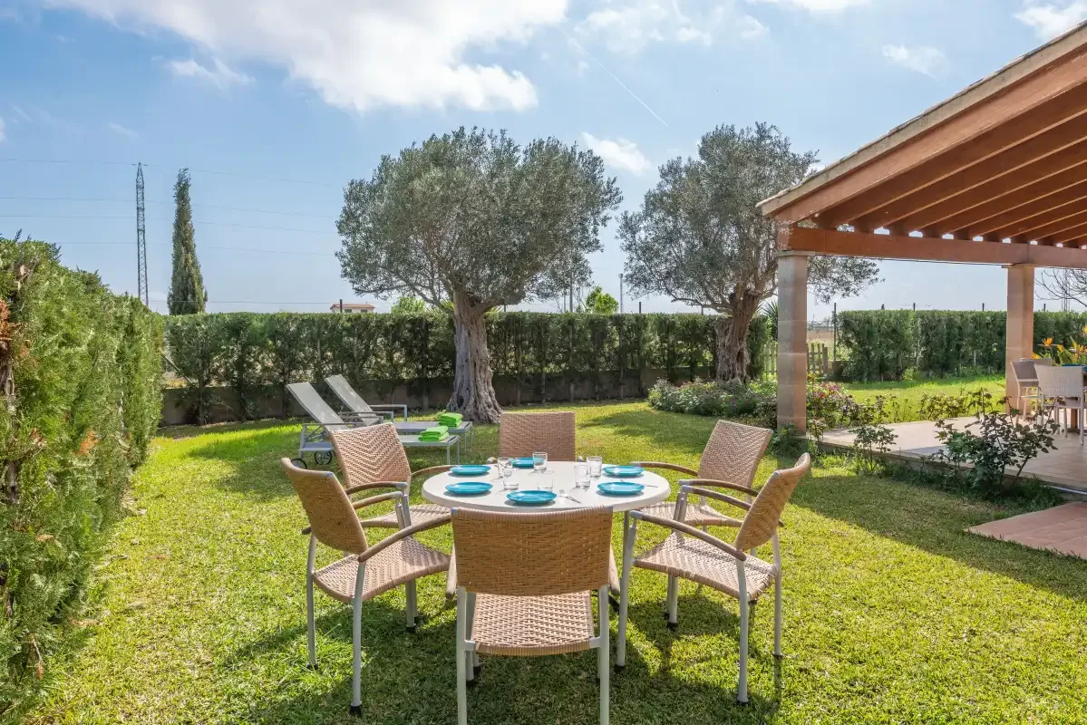 A garden patio with outdoor seating and a table set on the lawn.