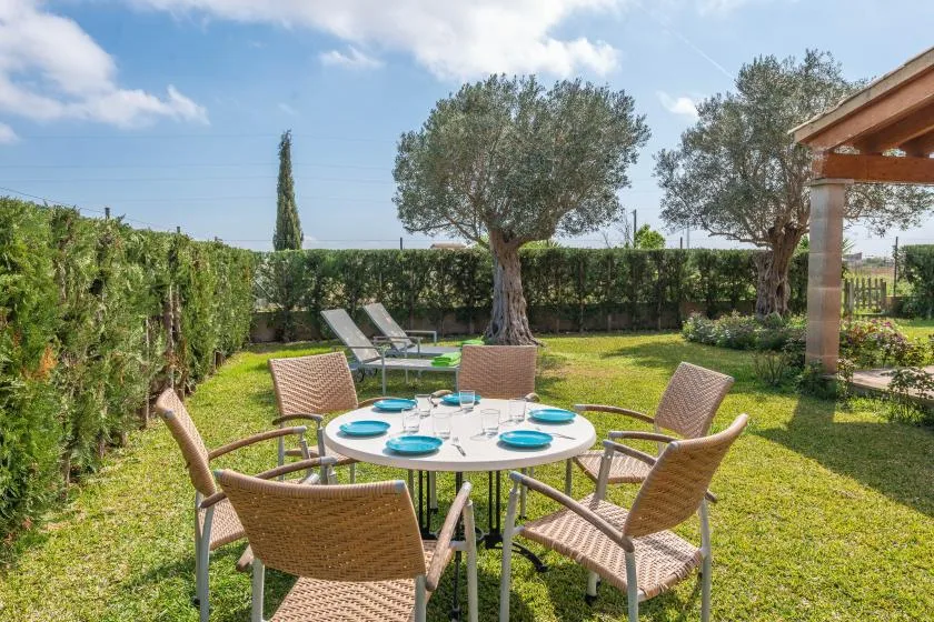 An outdoor dining area with a round table and seating in a garden.