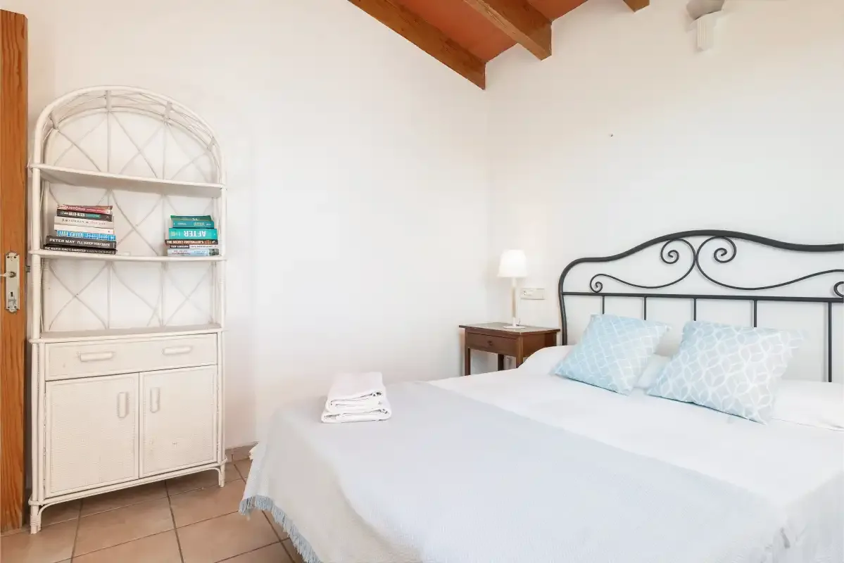 A bedroom with a bed, bedside table, and white cabinet.