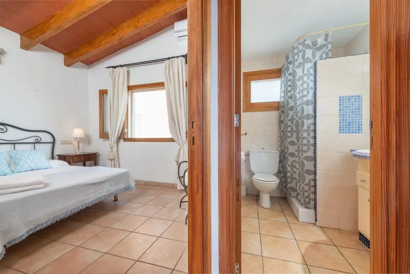 A bedroom and adjoining bathroom are visible through an open wooden doorway.