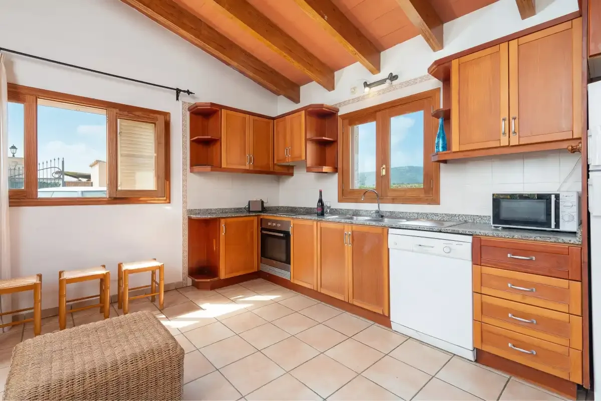 A kitchen with wooden cabinets, a tiled floor, and a dining table.