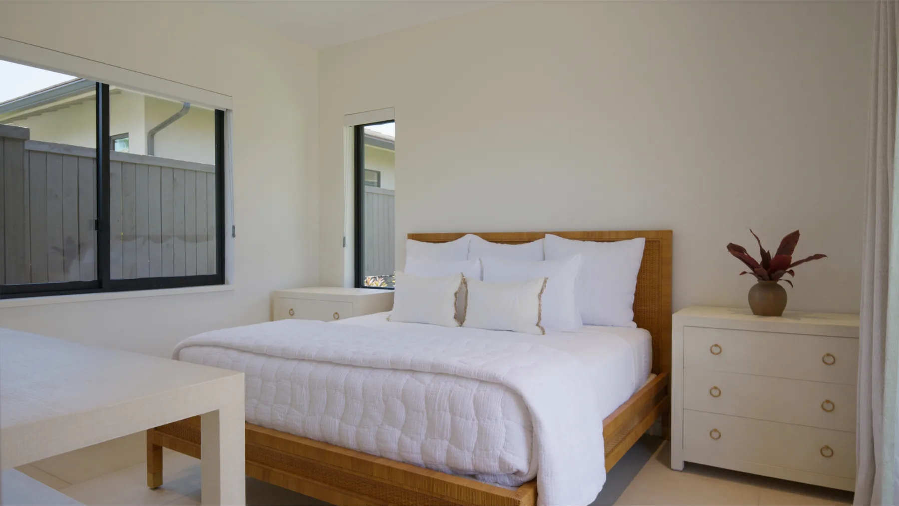 Un dormitorio luminoso con una cama bien tendida y cómodas junto a la cama.