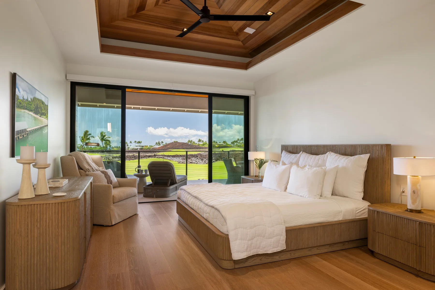 Un dormitorio con una cama grande y amplias ventanas con vistas a un paisaje verde.