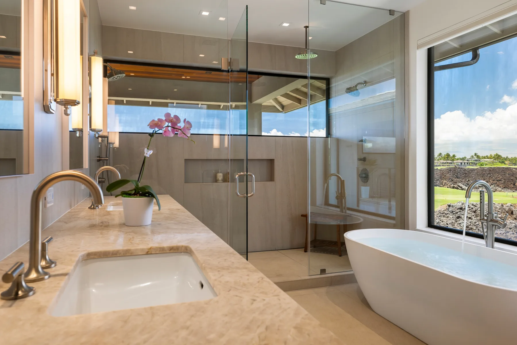 Un baño moderno con ducha de vidrio, bañera y un tocador largo.