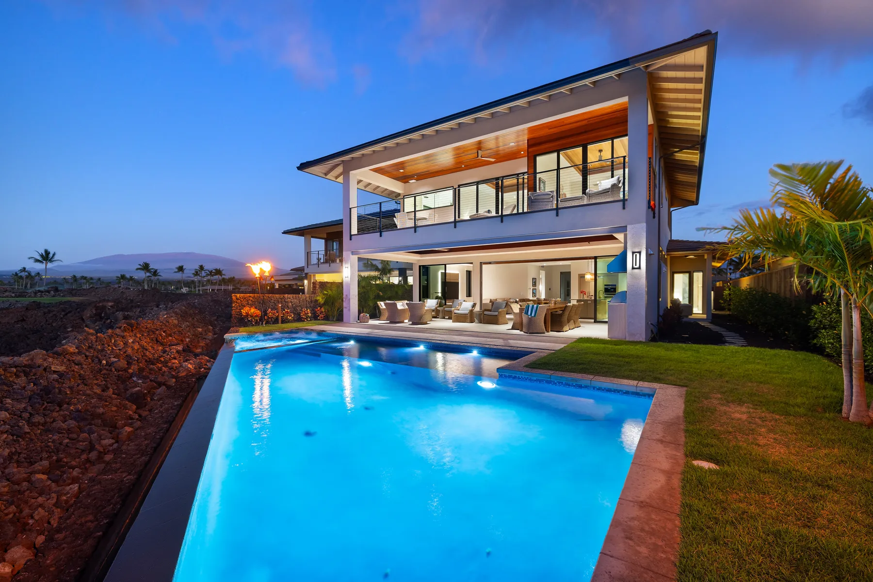 Una casa moderna da a una piscina al anochecer.