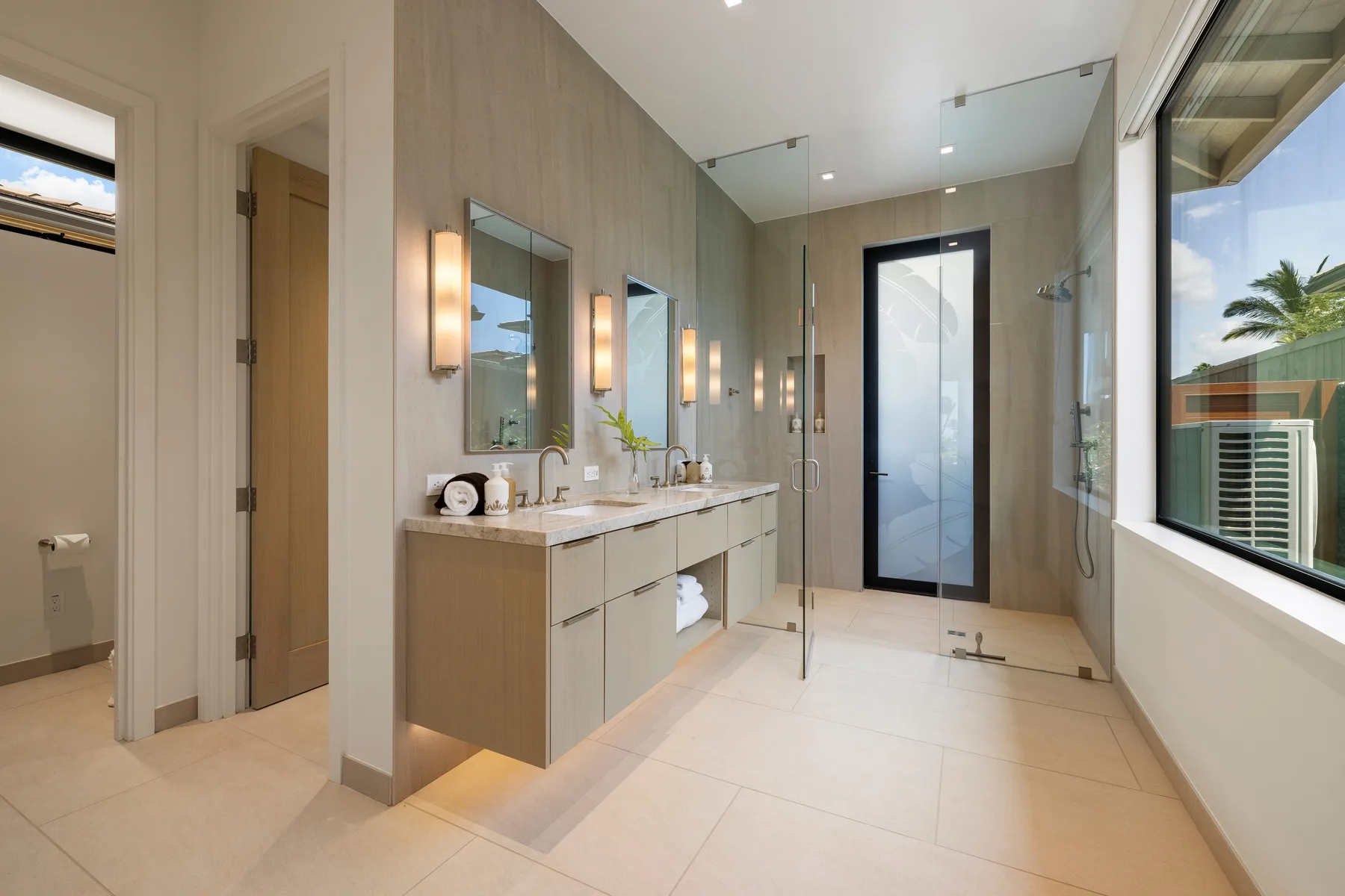 Un baño luminoso con un mueble de lavabo largo, espejos y una ducha de vidrio.