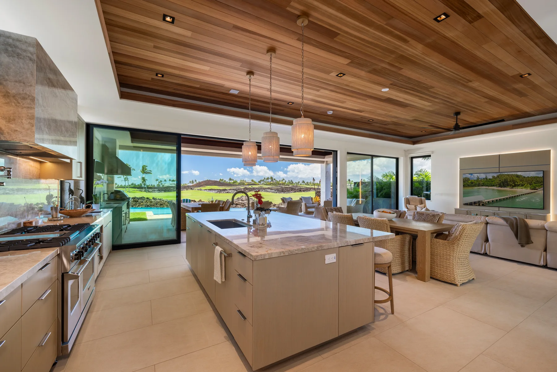 Una cocina y comedor abiertos, con una isla grande y ventanas amplias.