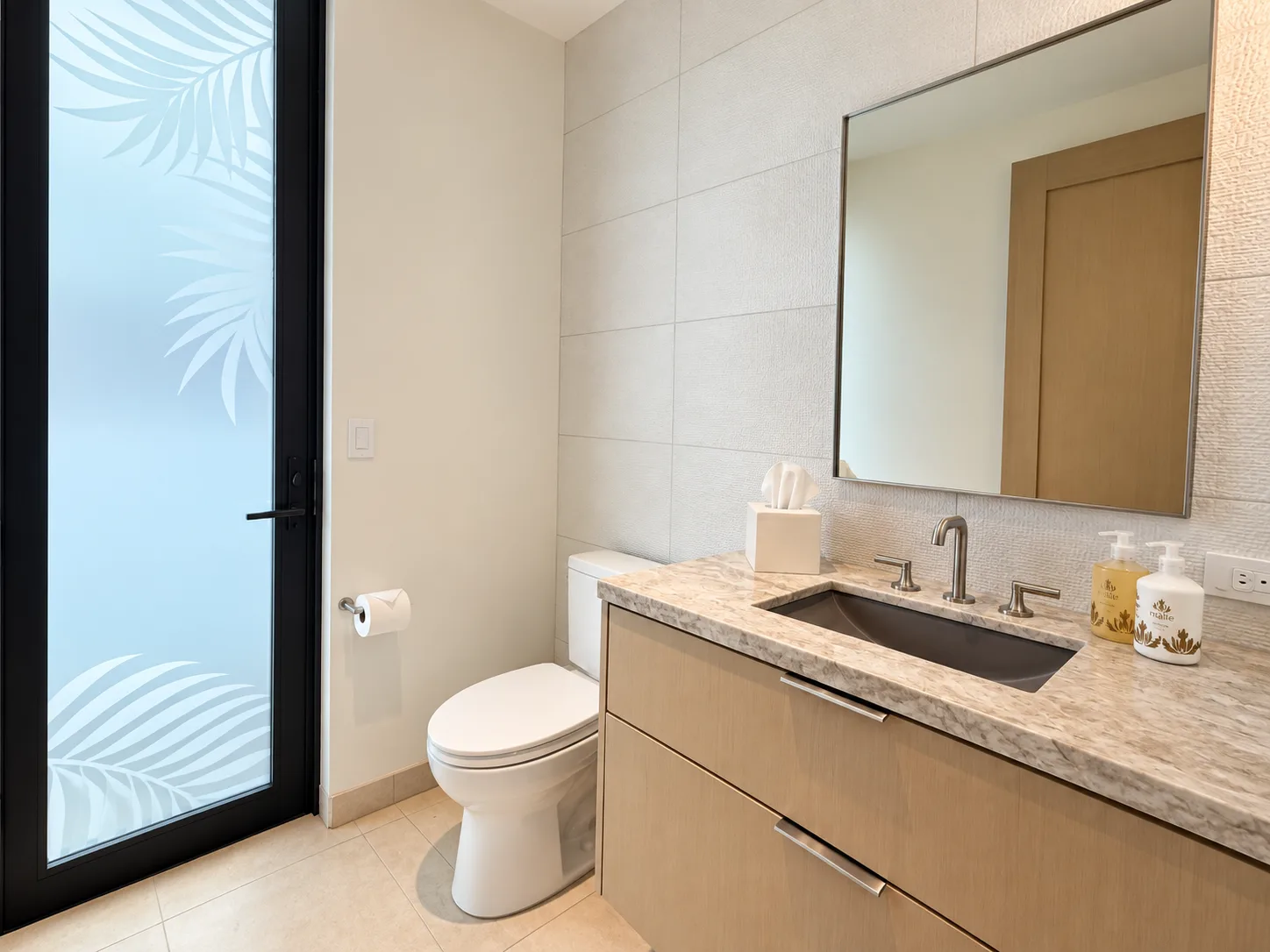 Un baño con inodoro, tocador y puerta de vidrio esmerilado.