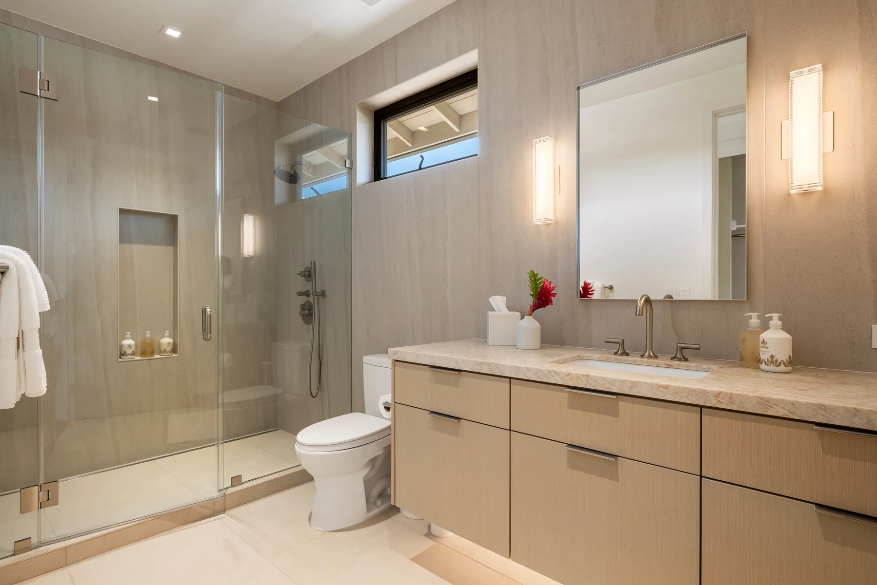 Un baño moderno con ducha de vidrio, inodoro y un largo tocador.