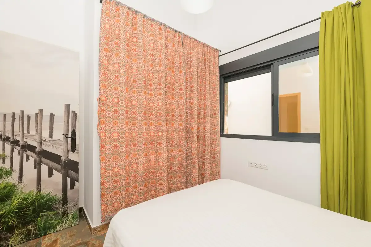 A bedroom with a bed, patterned curtains, and a window.