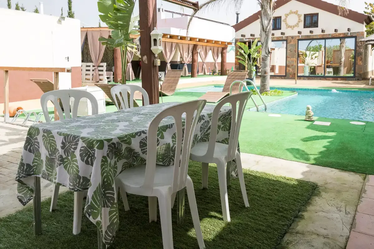 A poolside patio with a dining table and seating beside the water.