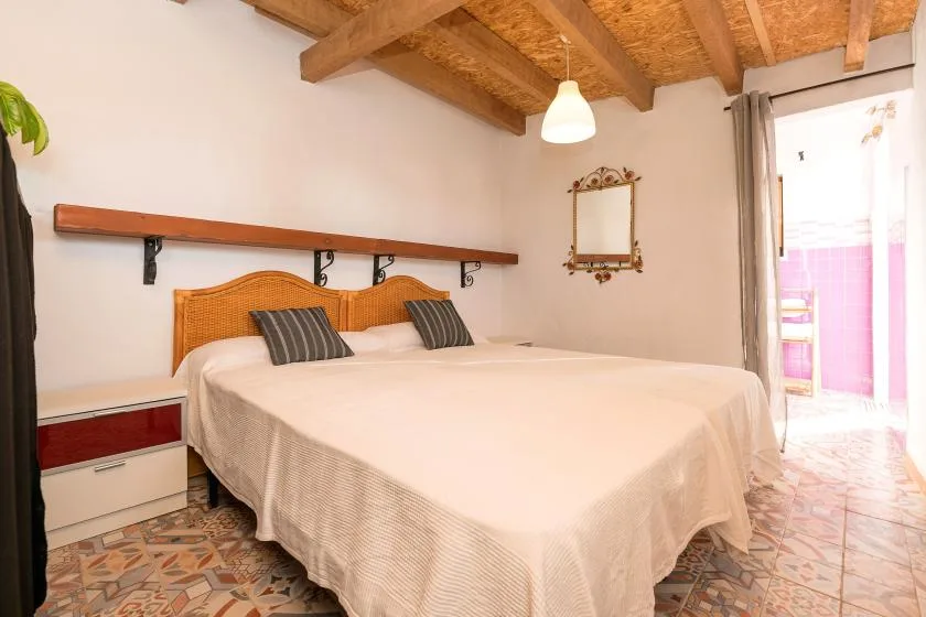 A bedroom with a large bed beneath exposed wooden ceiling beams.