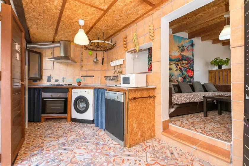 A compact kitchen opens into a dining and living area with patterned tile flooring.