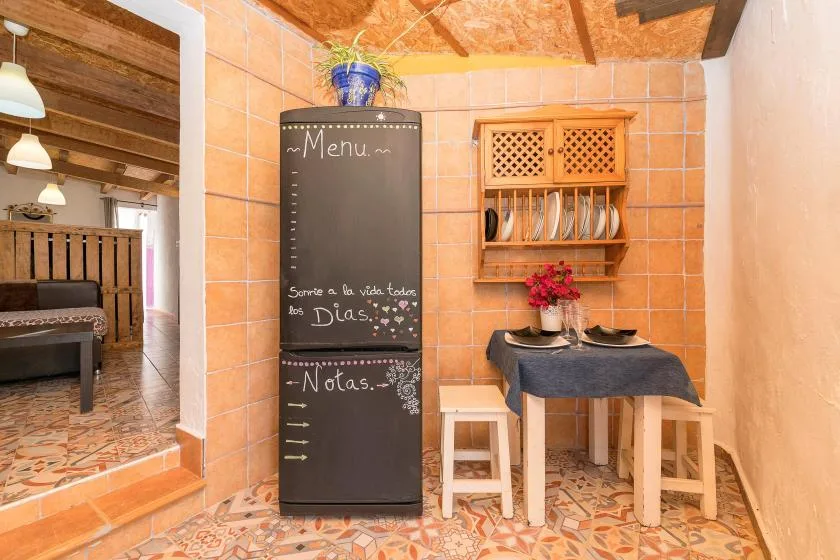 A tiled dining nook has a table, stools, and a chalkboard menu.