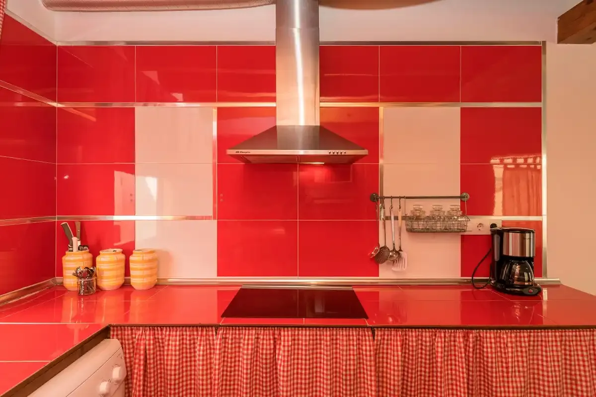 A red-tiled kitchen with a cooktop, range hood, and countertop.