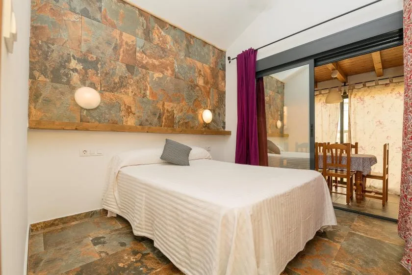 A bedroom with a bed beside a large stone-patterned wall panel.