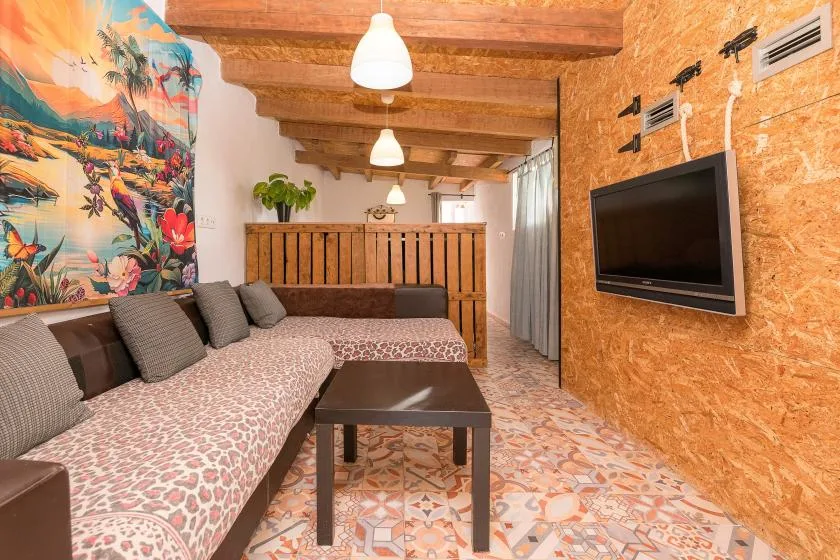 A colorful lounge area has patterned seating, a coffee table, and a wall-mounted television.