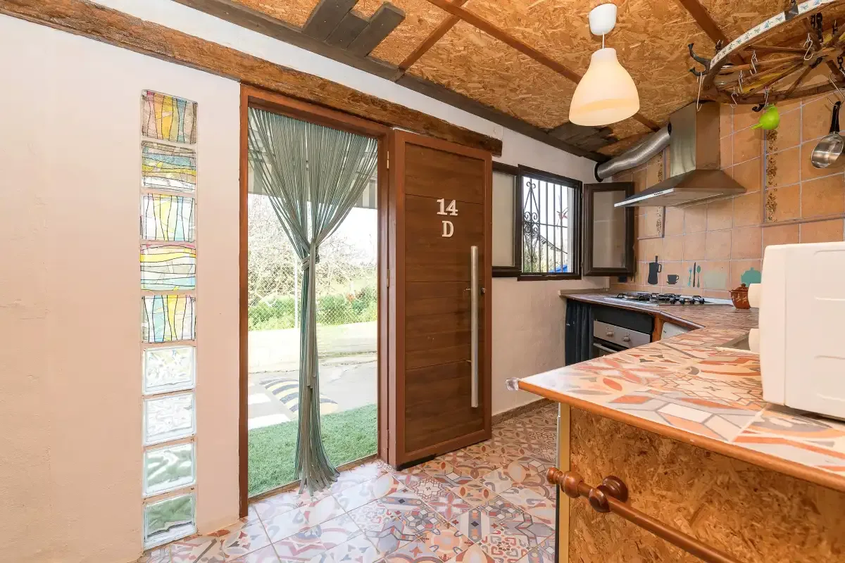 A kitchen with a tiled counter and a glass door opening onto a garden.