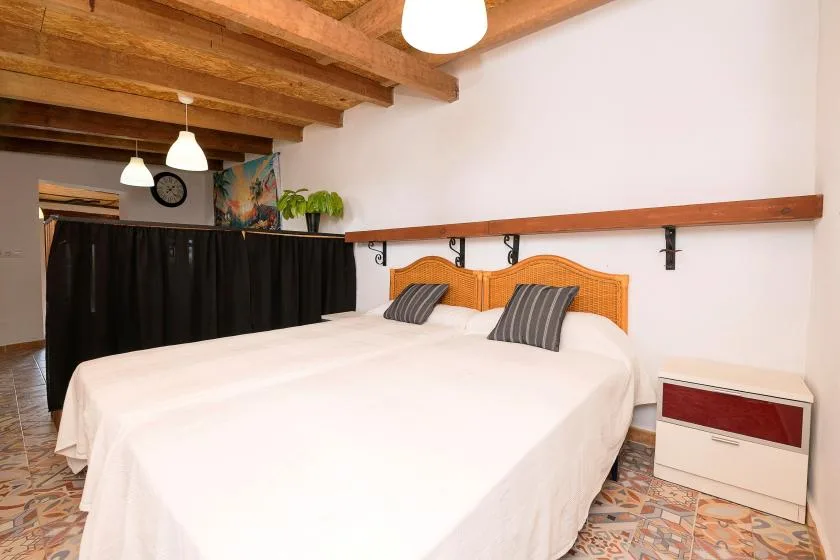 A bedroom with a large bed, wooden headboards, and exposed ceiling beams.