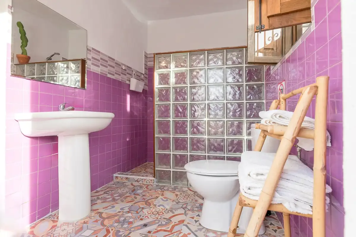 A tiled bathroom with a sink, toilet, and glass-block wall.
