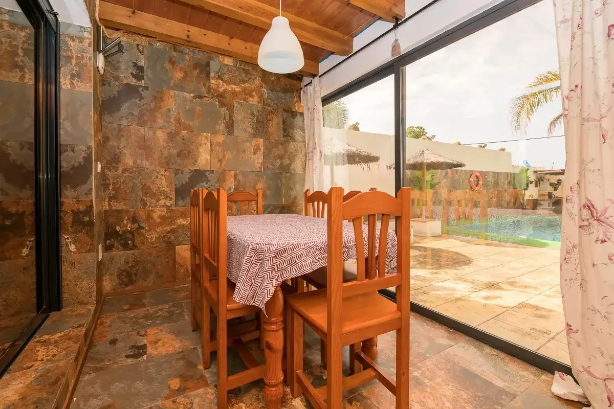A dining area with a wooden table and chairs beside large glass doors.